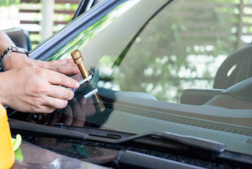 Glazier using tools repairing to fix crack windshield