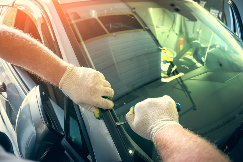 Service worker dismantle broken glass windscreen or windshield before installing new one on car in auto station garage