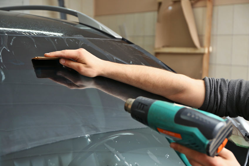 Worker applying tinting foil onto car window