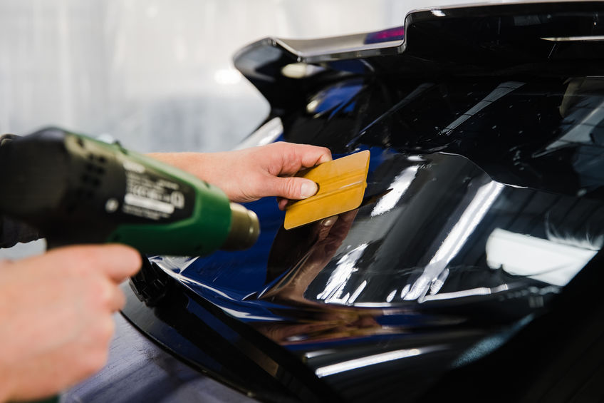 Car tinting. Worker applying tinting foil on car window at shallow depth of field