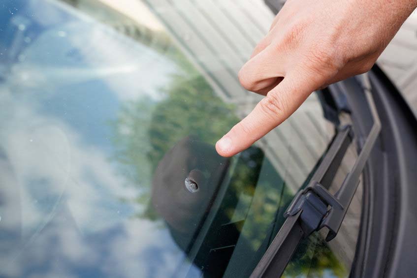 Glazier windscreen on Broken car windshield glass from stone poi Glazier windscreen on Broken car windshield glass from stone pointed watch of finger hand