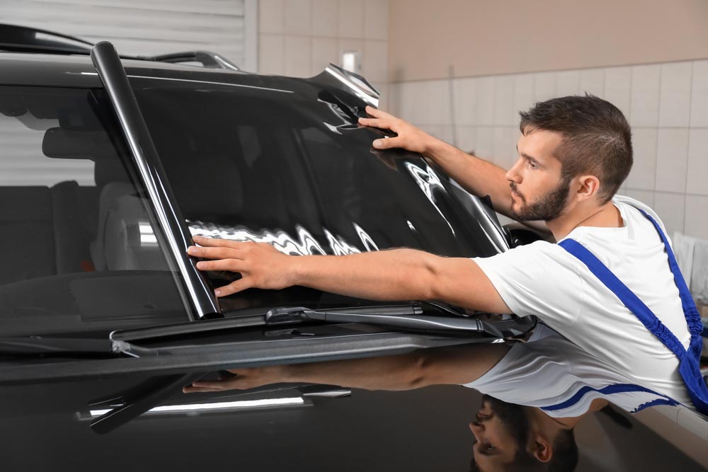 Worker tinting car window in shop