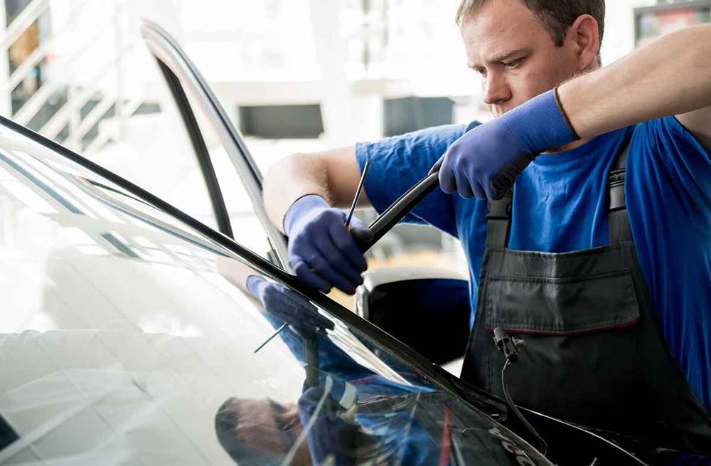 technicians removing windshield from a vehicle
